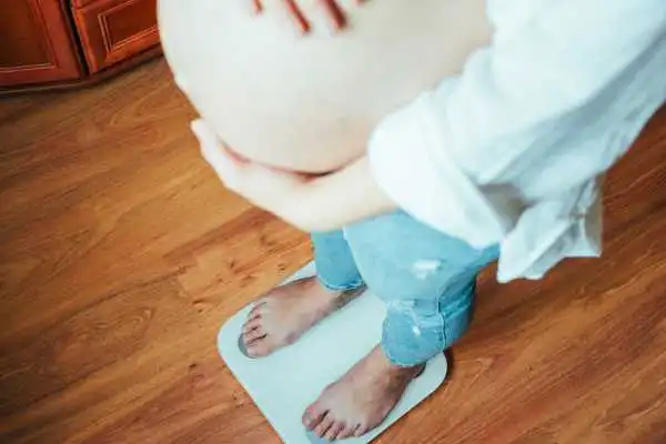 Image of woman weighing herself and experiencing weight gain through pregnancy Birchfield